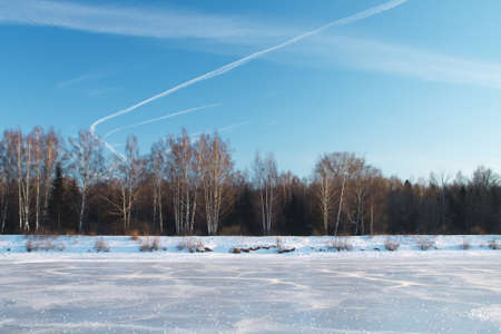 Winter landscape in the icy river. Landscape forms a horizontal strip of wood, ice, blue skyの写真素材