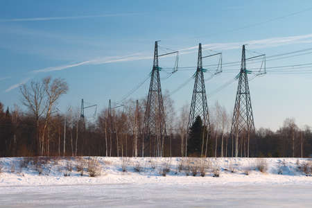Winter landscape in the icy river. Landscape forms a horizontal strip of wood, ice, blue sky. Power lines on the river bankの写真素材