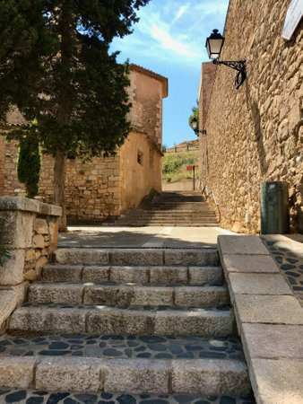 Montblanc, Spain, June 2019 - A stone building that has a bench in front of a brick wall. High quality photoの写真素材
