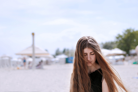 girl with long brown hair sitting on the beachの写真素材