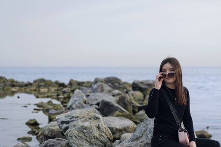 alone pretty girl by the sea with dark glasses