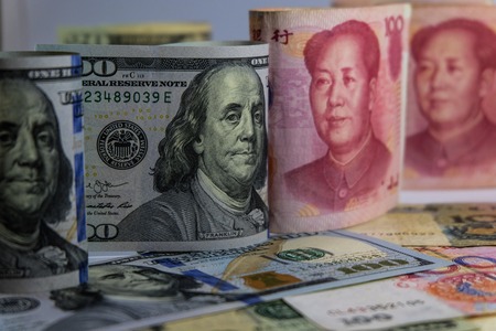 Face to face of Dollar and Yuan banknotes which its are the biggest economic country in the world. Now America and China have increase tax for import goods. It is tariff or barrier trade.の写真素材