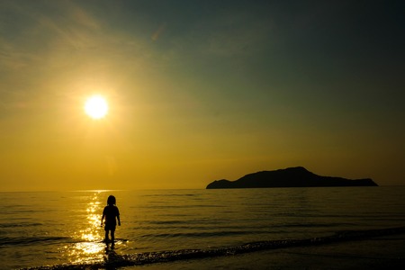 Alone girl standing on the beach with sunlight on summer vacation.Silhouette concept.の写真素材