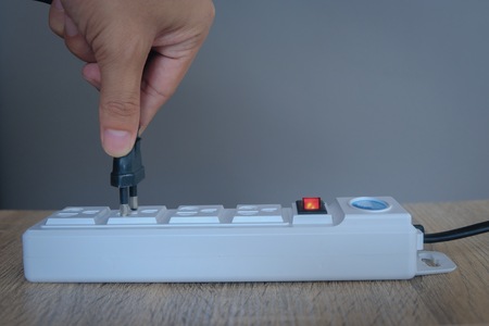 Male ' s hand unplugged from white socket to saving electric energy. reduce usage energy for save world concept.の写真素材