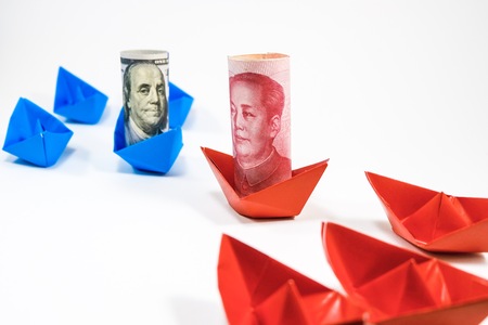 US dollar banknote on blue ship paper and Yuan China banknote on red ship paper on white backgroundの写真素材