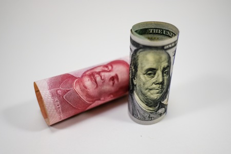 US dollar banknote roll stands up and China Yuan banknote down on white background.の写真素材