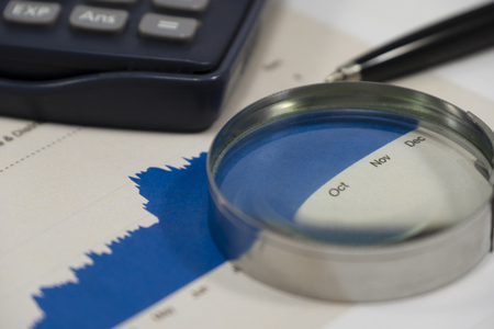 close up financial graph report with pen magnifier and calculator. This is financial report analysis is important for value investor concept.の写真素材
