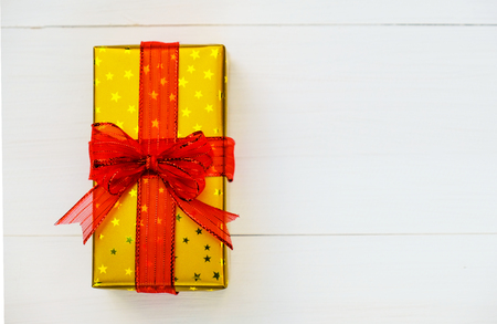 Christmas and Happy new year composition, Golden Christmas present gift boxes with red ribbon on wooden white background. Flat lay, top view, copy space.の写真素材