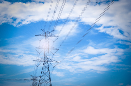 High voltage of electricity pole with cable on clouds blue sky and sun light.の写真素材