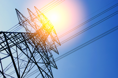High voltage of electricity pole with cable on clouds blue sky and sun light.の写真素材