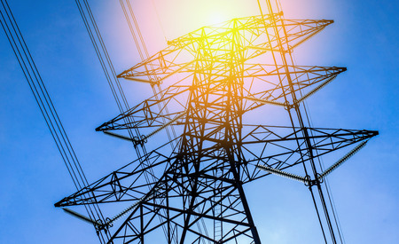 High voltage of electricity pole with cable on clouds blue sky and sun light.の写真素材