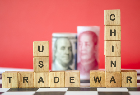 China and USA trade war wording on wooden cubes with US dollar and Yuan banknote. Trade war is economic tariffs tax barrier between China and United States of America which two biggest economy.の写真素材