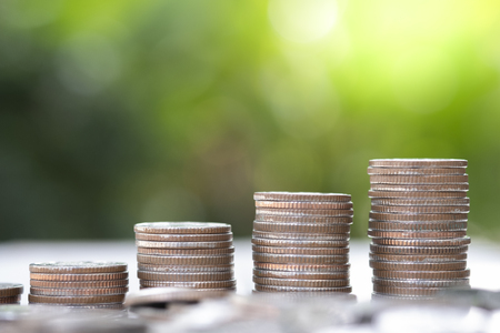 Closeup growing coins stacking with greenery background and sunlight. Saving  investment and profit...