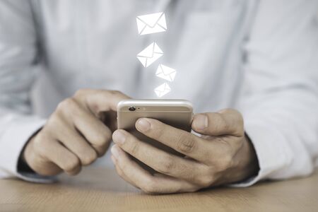 Businessman touching on mobile phone monitor to send electronic mail (E-mail). Work from home or everywhere.の写真素材