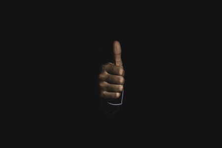 Businessman hand thumb up or like to good signal on black background.の写真素材