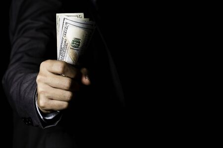 Businessman holding US dollar banknote on black background.USD is the main exchange currency in the...