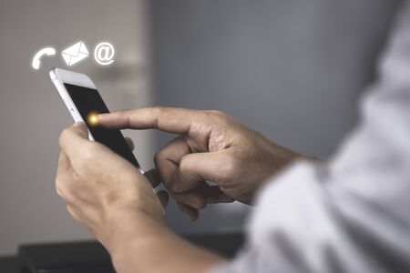 Businessman touching on mobile phone monitor to send electronic mail (E-mail). Work from home or...