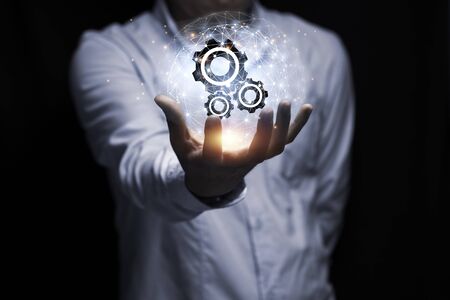 Businessman hand holding cog gear wheel infographic with sunlight. Engineering creative and business strategy concept.の写真素材