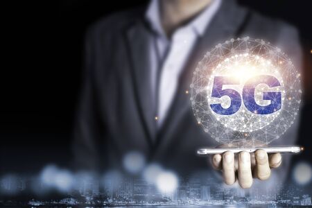 Businessman holding mobile phone with 5G infographic. 5 Generation wireless technology of mobile...