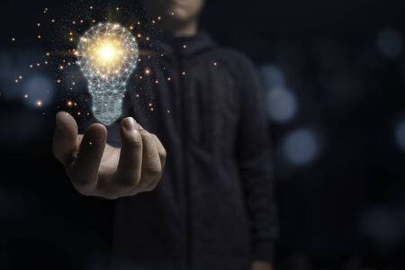 Businessman holding glowing virtual lightbulb with orange light . Creative new business idea...