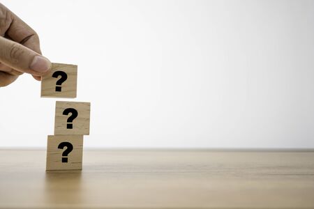 Hand putting question mark print screen on wooden cubes for Q&A or question and answer. Training Meeting and discussion concept.の写真素材
