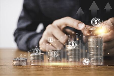 Businessman putting coins stacking with virtual graph and currency sign such as dollar pound sterling Yen Yuan and Euro . Business investment and saving profit concept.の写真素材