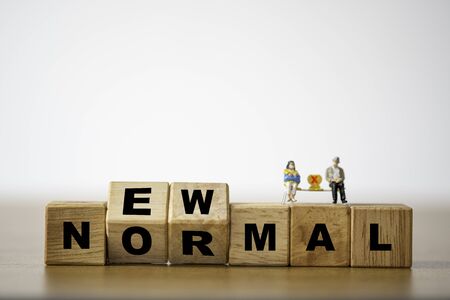Flipping wooden block cubes for new normal wording. The world is changing to balance it into new normal include living ,business , economy , environment and health.の写真素材