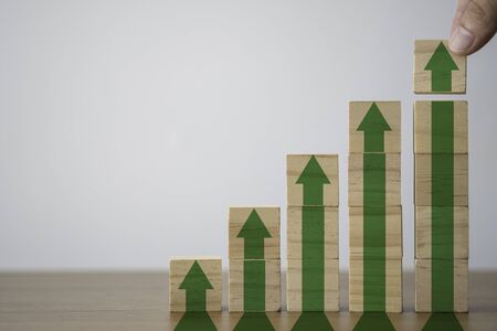 Hand putting wooden cubes block which print screen increase or up green arrow. It is symbol of economic investment profit growth.の写真素材