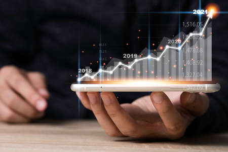 Hand holding mobile phone with virtual arrow and investment graph. Business and profit growth...