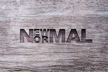 New normal wording carved on old wood. The world is changing to balance it into new normal include business , economy , environment and health.の写真素材