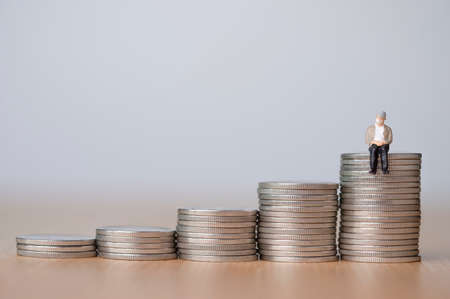 Aging society And saving money for retirement concept ,Old man sitting on coins stacking.の写真素材