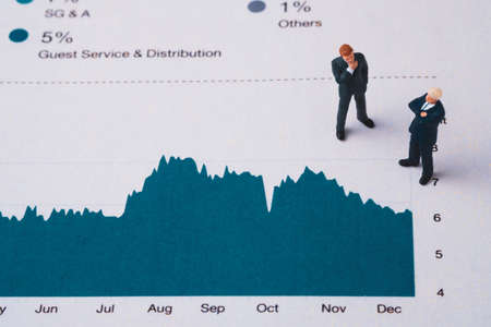 Businessmen miniature figure standing on investment and profit graph for analysis and discussion.の写真素材