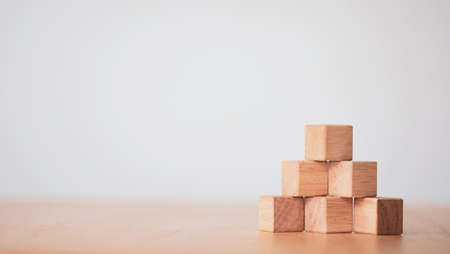 Hand putting and stacking blank wooden cubes on table with copy space for input wording and infographic icon.の写真素材