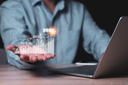 Businessman  holding to virtual investment bar and line graph on wooden table with laptop computer...