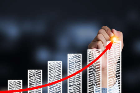 Businessman writing increase red arrow on bar chart.Business investor concept and profit rise up.の写真素材