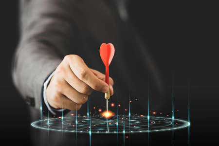 Businessman holding and throwing red arrow dart to virtual target dart board. Setup objectives and...