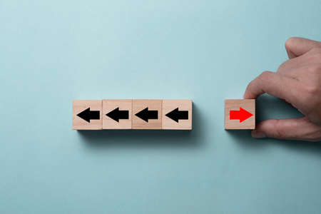 Hand putting putting cubes block for change direction of red arrow from left to right and black arrows. Disruption for new lift new business different thinking ,stand out and individual.の写真素材
