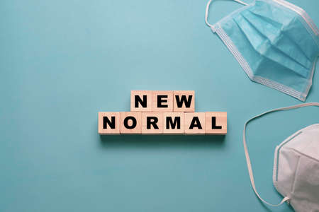 Flat lay of flipping wooden block cubes for new normal wording with surgical mask. The world is changing to balance it into new normal include business , economy , environment and health.の写真素材