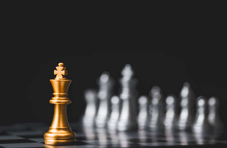 Golden king chess stand alone among  silver chess enemy at opposite side. Strategy decision for marketing business with competitors company concept.の写真素材