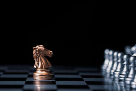 Golden horse chess encounters with silver chess enemy on chess board and black background. Market or business competitor concept.の写真素材
