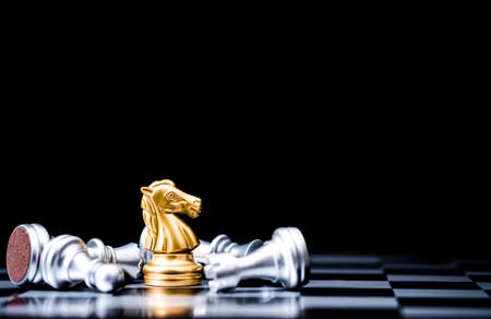Golden horse chess stand alone with fallen silver chess pieces. Winner of business competition and marketing strategy planing concept.の写真素材