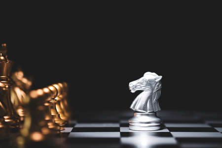 Silver horse chess encounters with gold chess enemy on chess board and black background. Market or business competitor concept.の写真素材