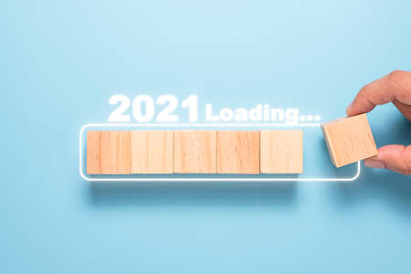Hand putting wooden cubes block to  white block for count down and loading to 2021. Happy new year to start new project and business concept.の写真素材