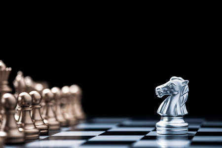 Silver horse chess encounters with gold chess enemy on chess board and black background. Market or business competitor concept.の写真素材
