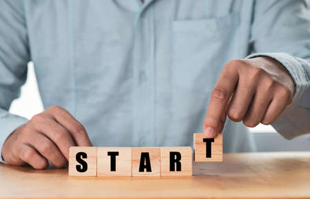 Businessman putting wooden cubes block which print screen start wording on table, start business and...
