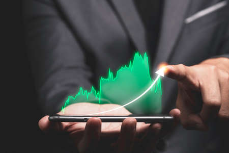 Economic and profit investment growth concept , Businessman holding smartphone and writing...