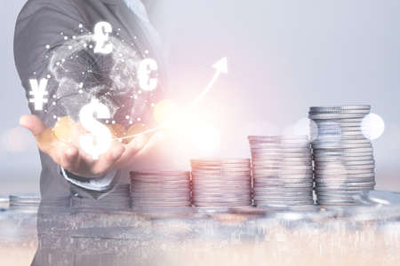 Investment saving and currency exchange concept , Double exposure of businessman holding dollar ,euro , pound sterling and Yen currency with coins stacking.の写真素材