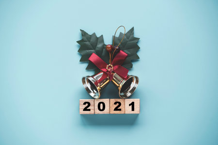 Flipping of wooden cubes block to change 2020 to 2021 year with golden bell on blue background. Merry Christmas and happy new year concept.の写真素材