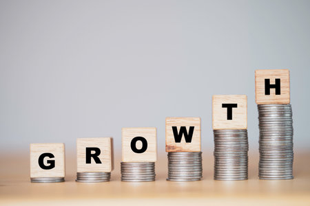 Business investment and profit growth concept, Growth wording on wooden block cube and lay down on coins stacking.の写真素材