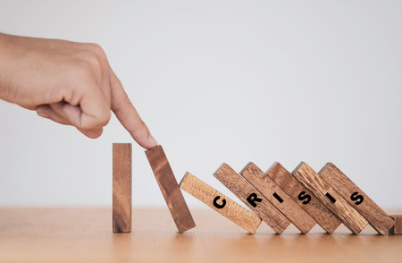 Stop crisis and risk management concept , Man using finger to stop wooden domino which falling to...